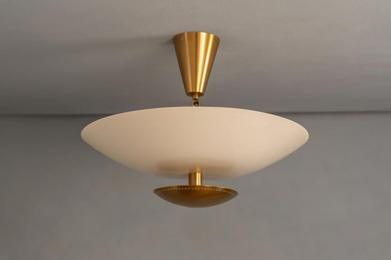 May include: A modern ceiling light fixture with a white, bowl-shaped shade and a gold-colored metal base and accents. The fixture is suspended from the ceiling by a gold-colored cone-shaped element.