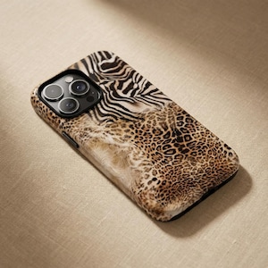 Puede incluir: Una funda de teléfono inteligente con un diseño de estampado animal único. La funda presenta una combinación de rayas de cebra, manchas de leopardo y una textura peluda. Tiene un módulo de cámara negro y un borde negro.