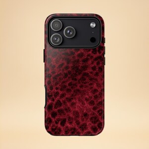 May include: A red and black patterned phone case. The case has a textured design and a black camera module with three lenses. The case is designed to fit a smartphone and offers protection and style.