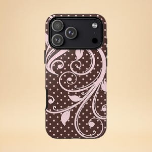 Könnte beinhalten: Braune Handyhülle mit rosa floralem Design und weißen Punkten. Die Hülle hat ein schwarzes Kameramodul mit drei Linsen.