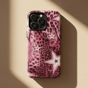 May include: A smartphone case with a pink leopard print design and white star accents. The case has a black camera module and a glossy finish. The overall aesthetic is bold and fashionable.