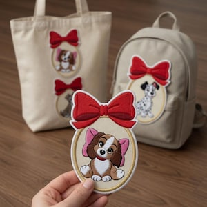 Op de afbeelding: Beige tote bag en rugzak met geborduurde patches van cartoonhonden en rode strikken. Een hand houdt een bijpassende patch vast. De patches tonen een bruin-witte hond, een Dalmatische hond en een bruine hond. De patches zitten in een cirkelvormige lijst.