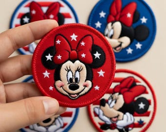 May include: Embroidered patches featuring Minnie Mouse in a patriotic theme. The patches are round, with a red background and white stars. Minnie Mouse is wearing a red bow. Other patches have a blue background with white stars and red and white stripes.
