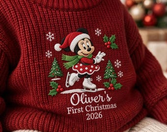 Puede incluir: Un suéter de punto rojo oscuro con un bordado de Minnie Mouse con gorro de Papá Noel, bufanda y patines de hielo. El diseño incluye pinos verdes, bayas de acebo y copos de nieve blancos. El texto dice Oliver's First Christmas 2026.