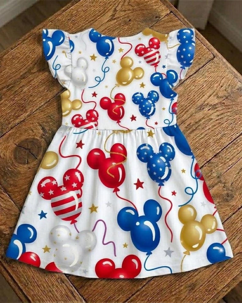 Get your little princess ready for the summer holidays with this absolutely adorable and festive dress. Featuring a beautiful Mickey Mouse balloon-themed print on a crisp white background—including red, white, blue, and gold Mickey-shaped balloons with ribbons and stars. This dress is the perfect outfit for a 4th of July celebration, a Disney park visit, or any patriotic summer party.