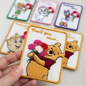 May include: Embroidered patches featuring Disney characters like Winnie the Pooh, Tinkerbell, Marie, and Daisy Duck, each holding a bouquet of flowers. The patches have a white background with a gold border and the text "Thank you, Mum..."