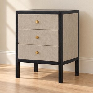May include: A three-drawer nightstand featuring a dark black wooden frame and light beige textured drawer fronts. Each drawer is equipped with a single small, hexagonal brass-colored knob centered on the front panel.