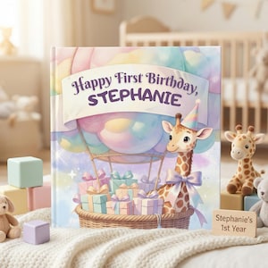 May include: A personalized children's book with the text "Happy First Birthday, STEPHANIE" on the cover. The cover features a giraffe in a hot air balloon with gifts. A small wooden sign reads "Stephanie's 1st Year". Soft pastel colors dominate the design.