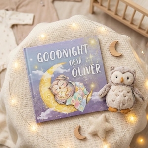 May include: A children's book titled "Goodnight Dear Oliver" with an illustration of a sleeping owl on a crescent moon. A plush owl toy, wooden moons, and a star are arranged on a cream-colored blanket, with fairy lights.
