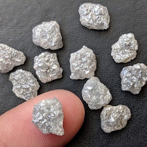 K&ouml;nnte beinhalten: Eine Sammlung von rohen, unpolierten, wei&szlig;en Diamanten. Die Diamanten sind in verschiedenen Gr&ouml;&szlig;en und Formen und haben ein nat&uuml;rliches, rohes Aussehen.