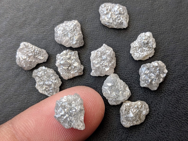 K&ouml;nnte beinhalten: Eine Sammlung von rohen, unpolierten, wei&szlig;en Diamanten. Die Diamanten sind in verschiedenen Gr&ouml;&szlig;en und Formen und haben ein nat&uuml;rliches, rohes Aussehen.