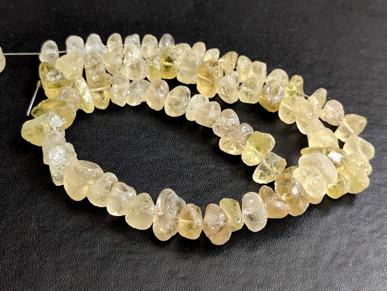 May include: A strand of light yellow, faceted, natural gemstone beads. The beads are irregular in shape and have a rough, natural finish.