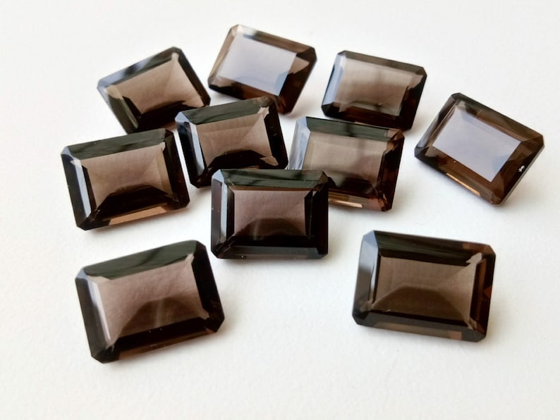 以下が含まれることがあります： 長方形のエメラルドカットの煙水晶の宝石が10個。宝石はファセットカットされており、濃い茶色をしています。