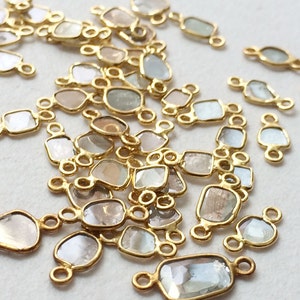 May include: A collection of gold-toned metal connectors with clear faceted gemstones. The connectors are designed to be used in jewellery making.