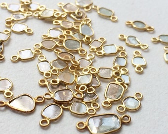 May include: A collection of gold-toned metal connectors with clear faceted gemstones. The connectors are designed to be used in jewelry making.