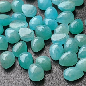 May include: A collection of loose, teardrop-shaped gemstones in a vibrant turquoise-blue color. Each stone features a smooth, polished, and rounded cabochon surface that reflects light, showcasing a translucent quality and consistent teal hue.