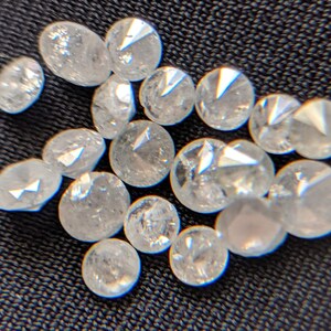 May include: A collection of small, clear, faceted diamonds, likely for jewelry making.