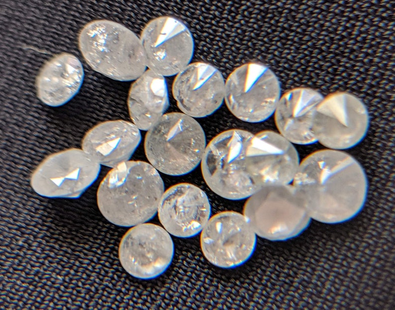 May include: A collection of small, clear, faceted diamonds, likely for jewelry making.