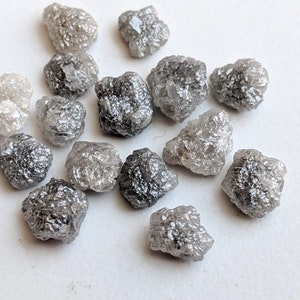 May include: A collection of rough, uncut, grey and white diamonds. The diamonds are various sizes and shapes.