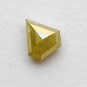 May include: A yellow, faceted, rough diamond with a kite shape.