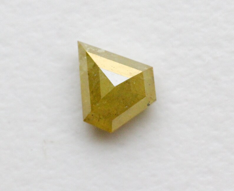 May include: A yellow, faceted, rough diamond with a kite shape.
