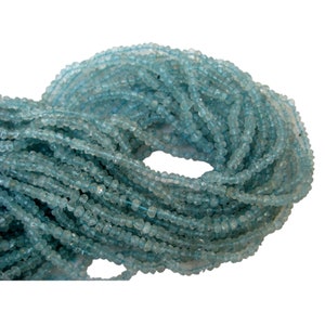 May include: A strand of light blue aquamarine beads, faceted and with a slightly irregular shape. The beads are strung on a clear thread and are approximately 4mm in diameter.