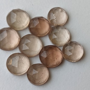 Puede incluir: Diez piedras preciosas redondas, facetadas, transl&uacute;cidas, de color marr&oacute;n claro. Las piedras preciosas tienen una calidad ligeramente iridiscente.