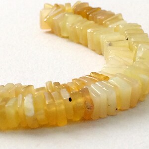 May include: A strand of yellow and white opal beads, each bead is a rectangular shape with a slightly pointed edge.