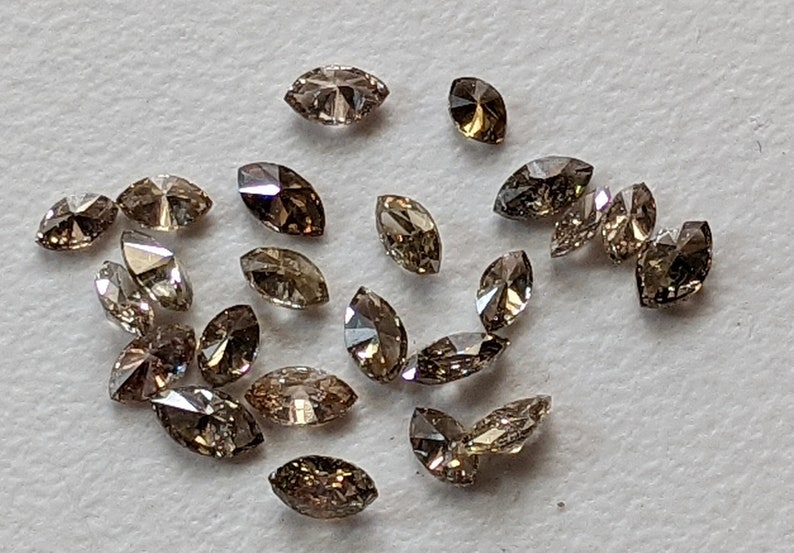 Puede incluir: Una colecci&oacute;n de diamantes marrones en forma de marquesa, con una variedad de tonos y tama&ntilde;os.