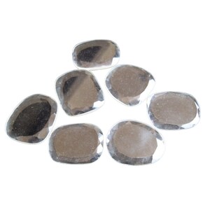 May include: Seven clear, faceted, oval-shaped stones. The stones are smooth and polished, with a slight shimmer.