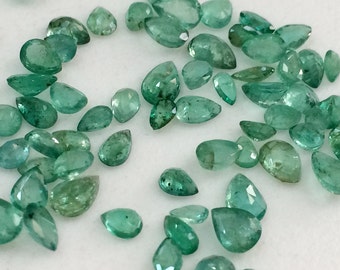 Puede incluir: Una colección de piedras preciosas de esmeralda en forma de pera, que varían en tamaño y tono de verde. Las piedras están facetadas y tienen un acabado liso y pulido.