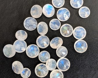 May include: A collection of 20 iridescent white moonstone cabochons. The stones are various sizes and shapes, with a smooth, polished finish.