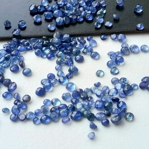 May include: A scattering of small, round, blue gemstones. The gemstones are smooth and have a slightly iridescent sheen.