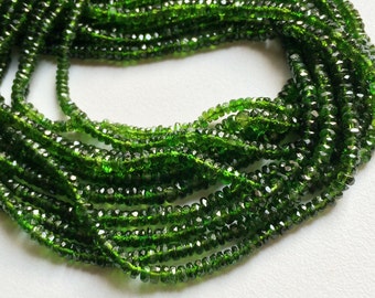 May include: A strand of green gemstone beads, likely peridot or green tourmaline, with a faceted, slightly irregular shape. The beads are strung on a clear thread and are approximately 3mm in diameter.
