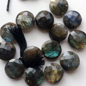 May include: A strand of faceted labradorite gemstone beads. The beads are a dark gray color with iridescent blue and green flashes. The beads are round and have a smooth, polished finish.
