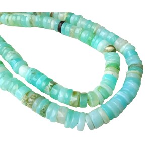 May include: A strand of turquoise blue opal beads, each bead is a different shade of blue and green, and has a slightly irregular shape.