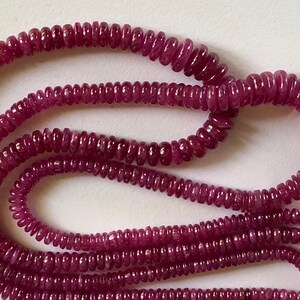 May include: A strand of pink ruby beads, each bead is a small, round, and slightly elongated shape.