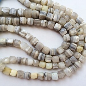May include: A strand of white and gray agate beads, each bead is faceted and has a square shape.