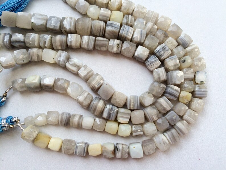 May include: A strand of white and gray agate beads, each bead is faceted and has a square shape.