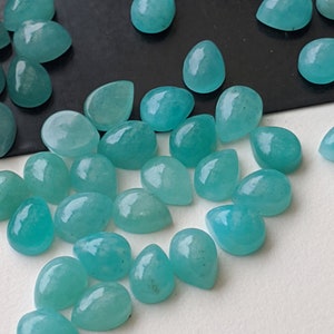 May include: A collection of loose, teardrop-shaped cabochons in a vibrant turquoise-blue color. These polished gemstones feature a smooth, rounded surface and a flat back, displaying subtle natural variations in their opaque, solid color.