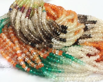 May include: A close-up of a variety of gemstone beads in different colors, including clear, brown, green, and orange. The beads are small and round, and they are arranged in a pile.