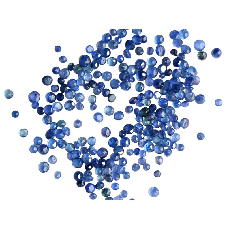 May include: A scattering of small, round, blue gemstones. The gemstones are various shades of blue, from light to dark.