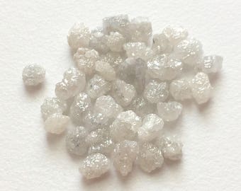 May include: A pile of small, white, rough diamonds. The diamonds are various shapes and sizes.