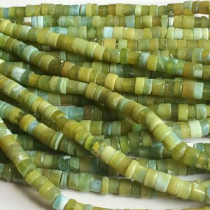 May include: A strand of green and blue jade beads. The beads are small and round, and they are strung together on a thin wire. The beads are a light green color with some blue and white streaks.