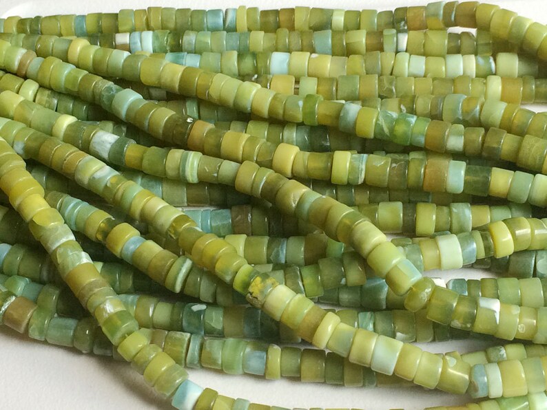 May include: A strand of green and blue jade beads. The beads are small and round, and they are strung together on a thin wire. The beads are a light green color with some blue and white streaks.