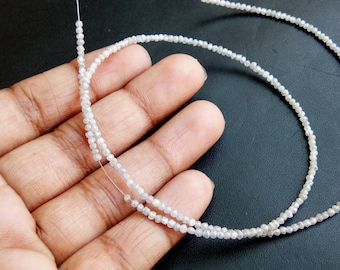 May include: A strand of white diamond beads strung on a thin wire. The beads are small and round, and they are arranged in a single row.