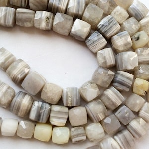 May include: A strand of white and gray agate beads, each bead is faceted and has a square shape.