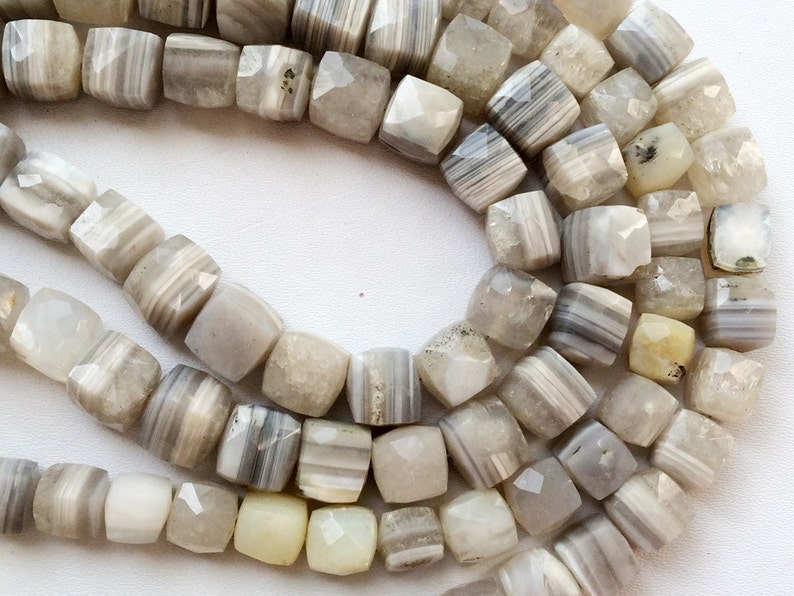 May include: A strand of white and gray agate beads, each bead is faceted and has a square shape.