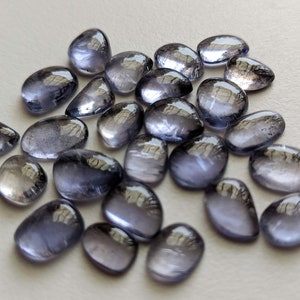May include: A collection of 20 smooth, oval-shaped, translucent, light blue gemstones. The stones have a slightly iridescent quality.