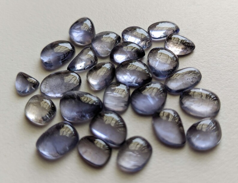 May include: A collection of 20 smooth, oval-shaped, translucent, light blue gemstones. The stones have a slightly iridescent quality.